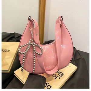 Detail of pink cracked leather hobo bag with Fashion embossing and beaded bow charm