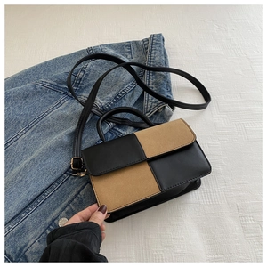 Detail of a two-tone crossbody bag with black faux leather and tan suede patchwork