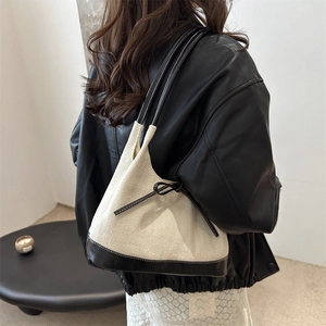 Minimalist cream canvas tote bag with black leather trim and bow detail on the shoulder