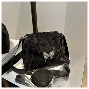 Detail of black pleated crossbody bag with silver butterfly buckle and small round pouch