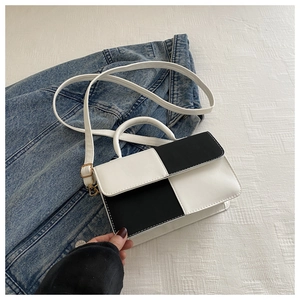 Detail of contrast patchwork texture and golden hardware on small crossbody bag
