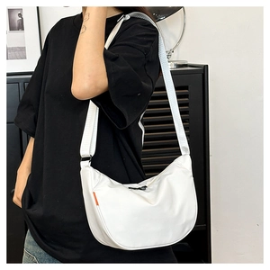 White nylon crescent crossbody bag with adjustable wide strap and orange detail on model