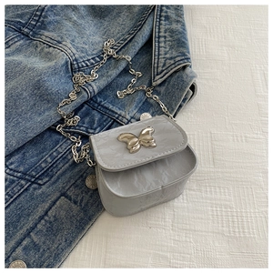 Detailed close-up of marble texture mini bag with metal butterfly and silver chain