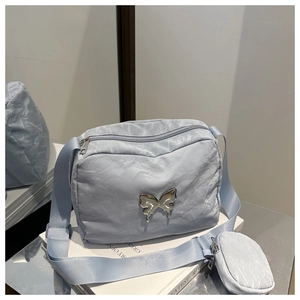 Detail of light blue crossbody bag with silver butterfly charm and detachable coin purse