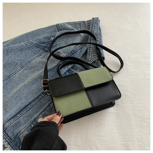 Detail shot of black and sage green patchwork leather handbag with magnetic flap closure