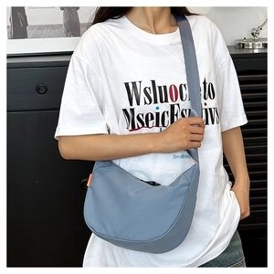 Close-up of light blue nylon crescent bag with adjustable grey strap and orange detail