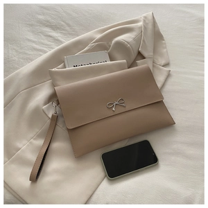 Close-up of khaki envelope clutch featuring a silver bow buckle and leather wristlet strap