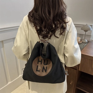 Minimalist canvas backpack with brown leather straps and vintage logo tag shown on model