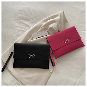 Flat lay of vintage style envelope clutch bags in black and rose red with metal bows