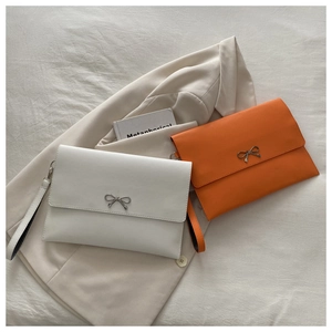 Detail of white and orange envelope clutch bags with silver metal bow and wrist straps