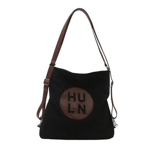 Large black canvas tote bag with brown leather straps and adjustable shoulder handle