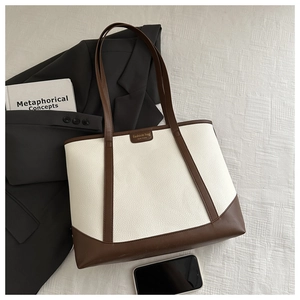 Flat lay of a leather tote bag with patchwork design alongside office accessories