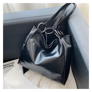 Detailed close-up of glossy black tote bag with silver metal ring and sleek strap
