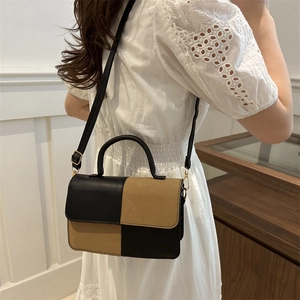 Women's chic contrast color handbag in black and brown patchwork leather shown on model