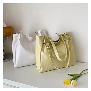 Detail of white and cream PU leather tote bags with distinctive silver metal ring hardware