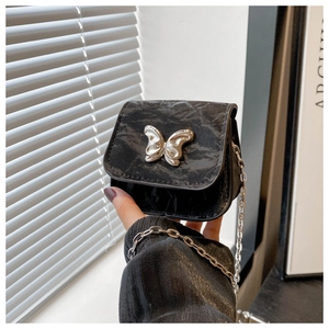 Detail of black pleated mini bag featuring silver butterfly buckle and delicate chain