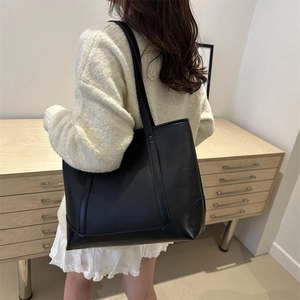 Classic large black leather tote bag with lychee texture shown on a female shoulder