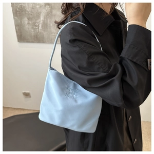 Close-up of light blue bucket bag with pretty and liberty embroidery on nylon fabric