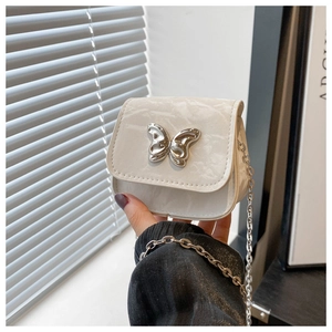 Close-up of a white leather saddle bag featuring a silver liquid metal butterfly buckle