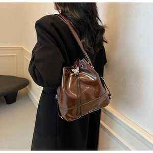 Close-up of vintage dark brown polished leather bucket bag with silver butterfly charm