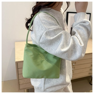 Detail of avocado green nylon hobo bag with pretty and libety embroidery on shoulder