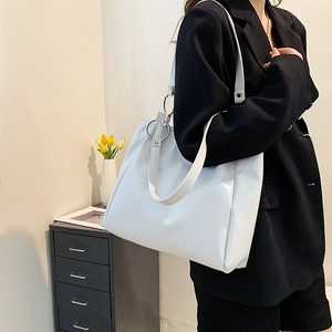 Minimalist white PU leather tote bag with silver metal rings shown on model shoulder