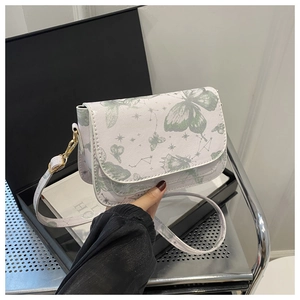 Close-up of white crossbody bag with green butterfly print and gold hardware detail