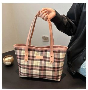 Detail of pink plaid pattern on fabric tote bag with leather strap and golden rivets