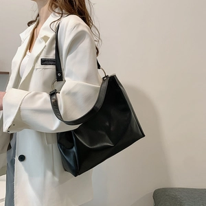 Minimalist black tote bag with large metal ring buckle, styled on model for professional look