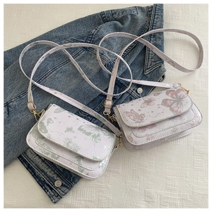 Detailed macro view of white leather crossbody bags with butterfly and star prints