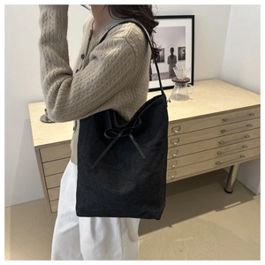 Detail of black canvas bucket bag with bow tie design and long shoulder strap