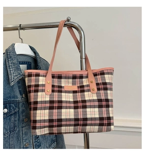 Detail of pink plaid tote bag with CAMISETA leather label and gold rivet accents