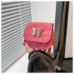 Detail of a bright pink mini crossbody bag featuring a silver butterfly buckle and chain