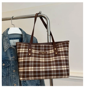 Close-up of retro plaid tote bag with leather handles hanging on a metal rack