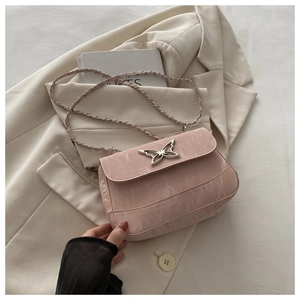 Detailed view of light pink leather crossbody bag with silver butterfly metal clasp