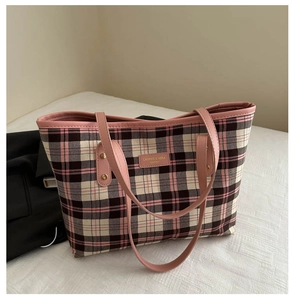 Detail of pink and black plaid tote bag with leather logo patch and metal rivets