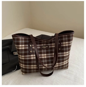 Detail of retro plaid tote bag showing leather straps and gold rivet reinforcements