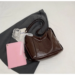 Deep brown faux leather tote bag detail with embossed number 10 and white lace bow accessory