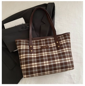 Macro detail of plaid texture and leather logo tag on a vintage-style tote bag