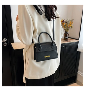 Close-up of black lychee-grain leather handbag with yellow FASHION text and gold hardware