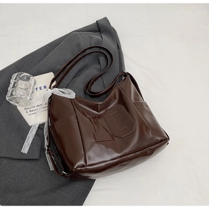 Detail of a brown PU leather tote bag with number embroidery and a white lace ribbon