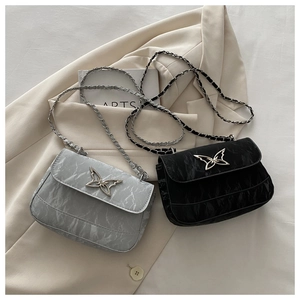Chic butterfly clasp crossbody bags in grey and black displayed on a beige blazer