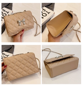 Detail view of beige quilted crossbody bag featuring silver bow buckle and chain strap