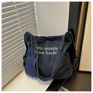Détail du tote bag en jean bleu foncé avec broderie blanche Less Monday More Sunday