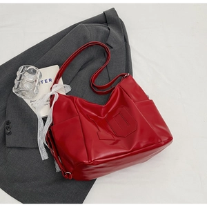 Detail of red oversized tote bag featuring embossed number 10 and white lace ribbon