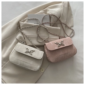 Close-up of elegant metal butterfly buckle and chain strap on stylish small square bags