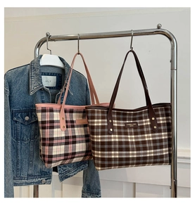 Detail of plaid tote bags with leather straps and logo patch on metal display rack