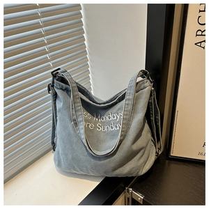 Détail du sac cabas en denim bleu clair avec broderie blanche sur un rebord de fenêtre