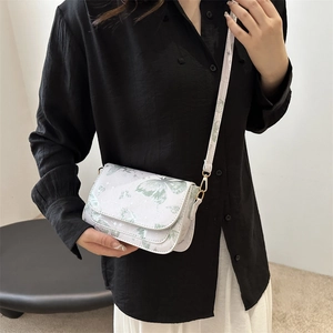 White crossbody bag with green butterfly print and gold metal clasp on female model