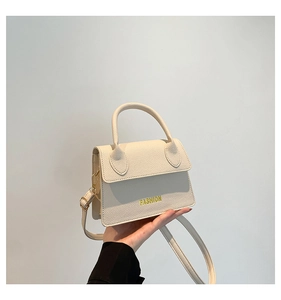 Close-up of beige lychee grain leather handbag with gold Fashion text detail